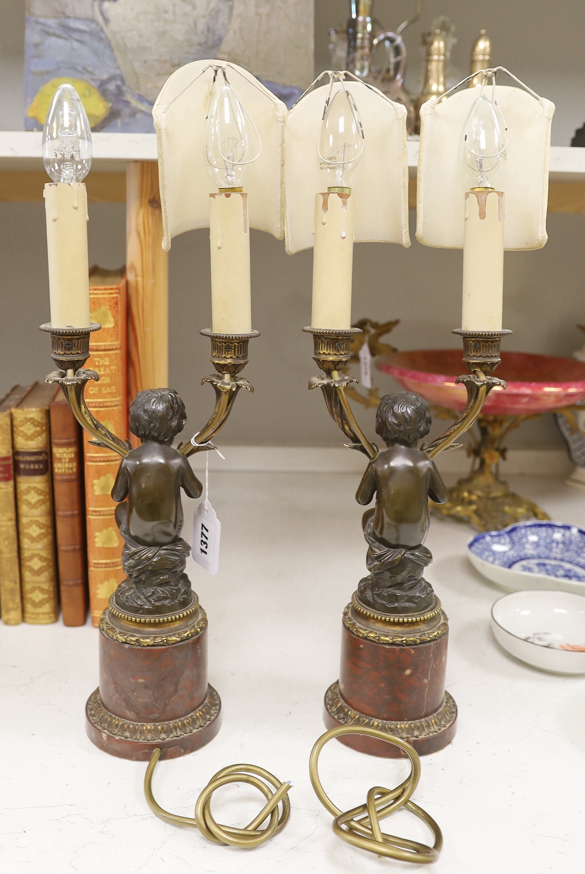 A pair of late 19th century French bronze and ormolu cherub two branch candelabra, converted to lamps, 49cm high including light fitting and bulb